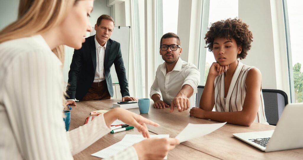 Business meeting. Group of young business people looking at documents and discussing something while sitting at the office table