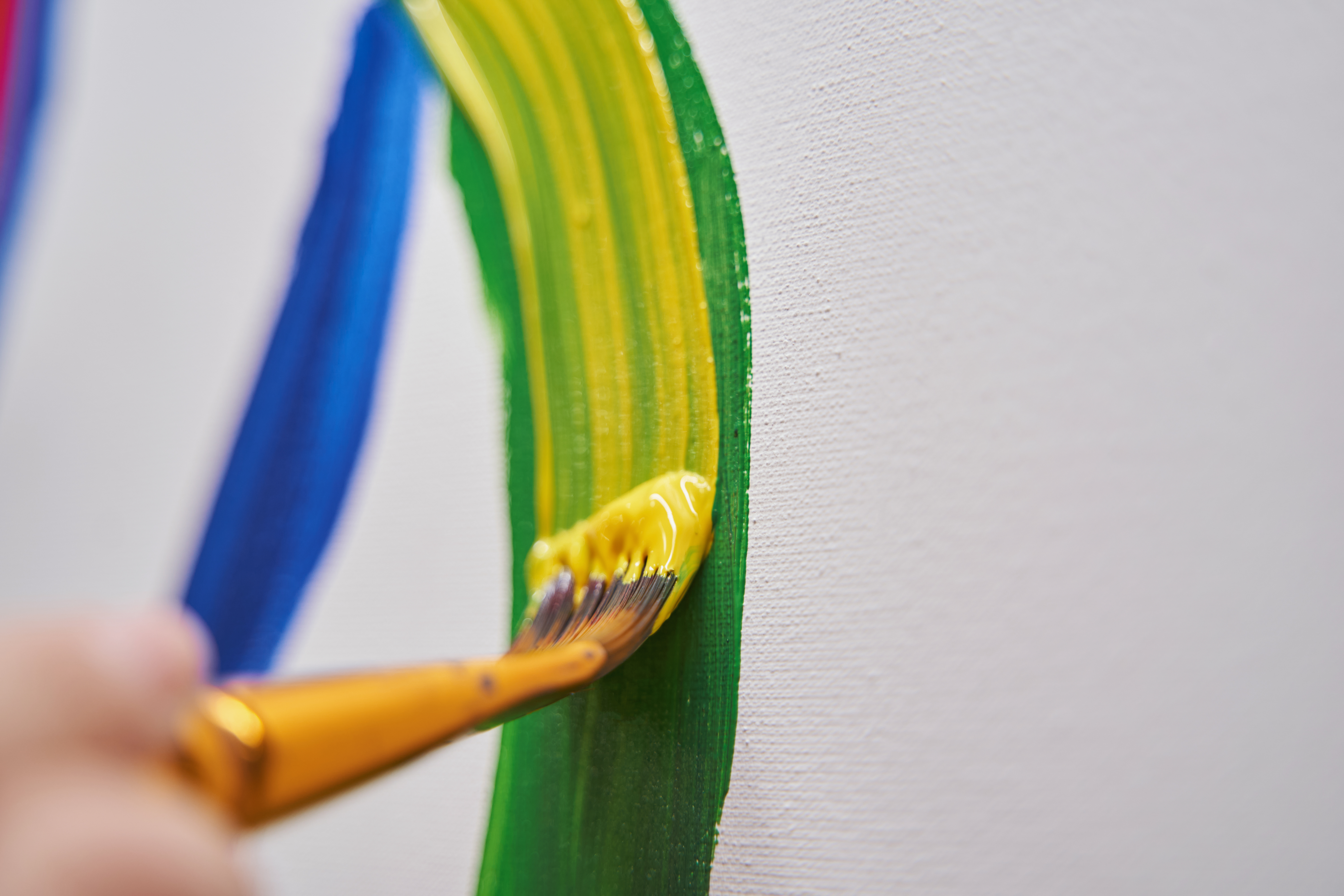 Close up of artist drawing bright lines Professional art brush being in female hand while painting on canvas